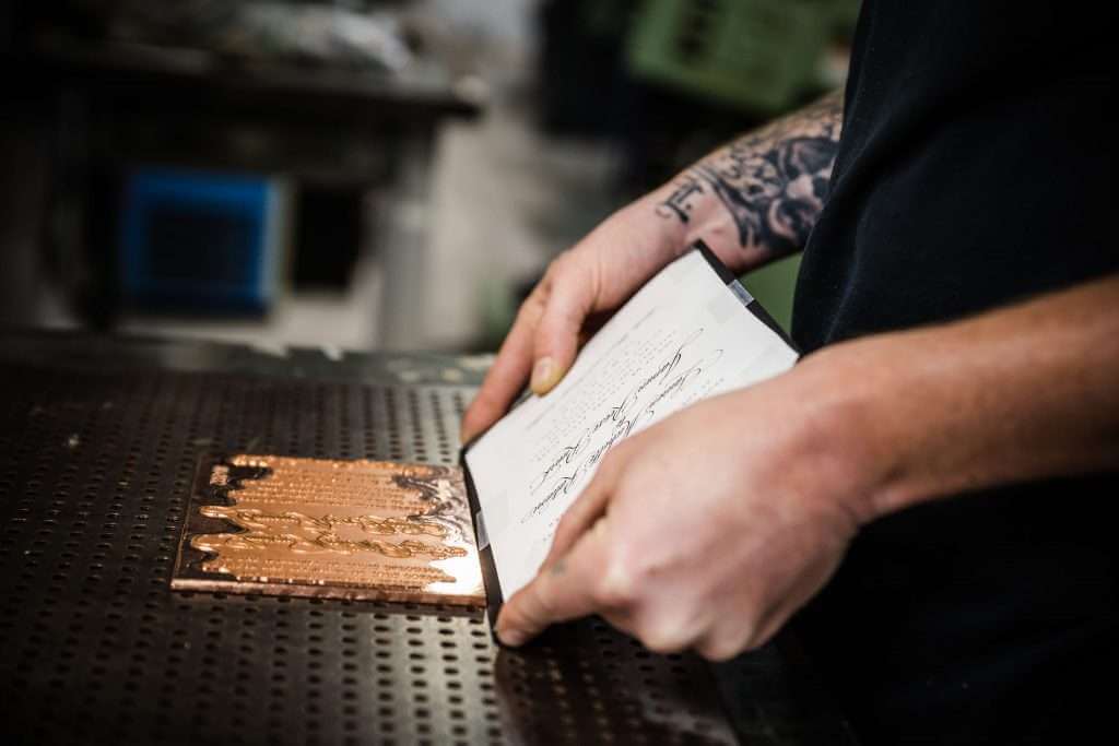 Man using a letterpress machine on an invitation