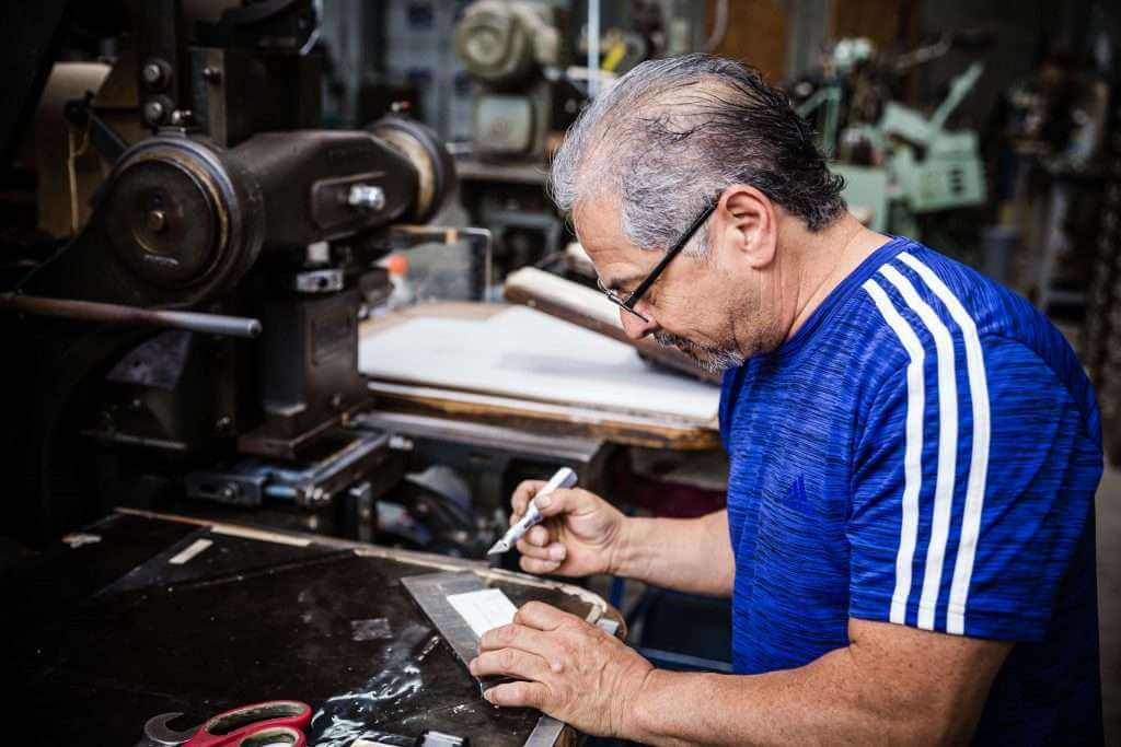 Man using a machine to letterpress an invitation