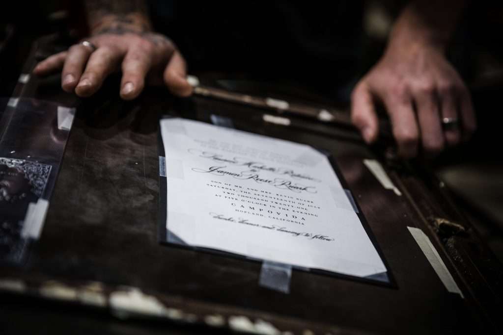 Man using a machine to letterpress an invitation