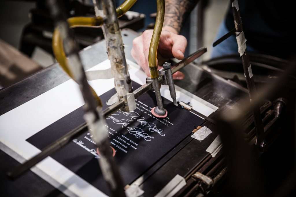 Man using a machine to letterpress an invitation